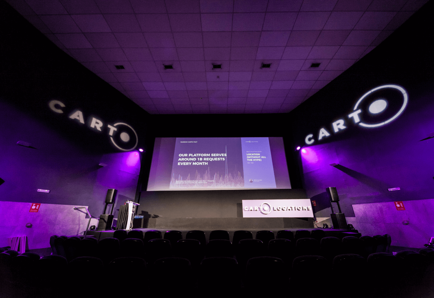 Carto Locations venue, with the logo projected over the walls and purple lights lighting the space